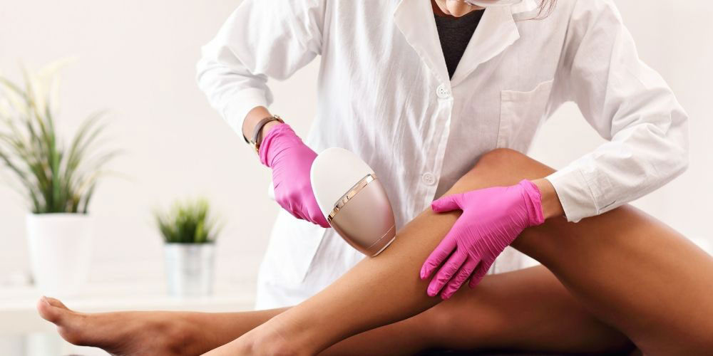 Dermatologist or Esthetician doing laser hair removal on womans leg